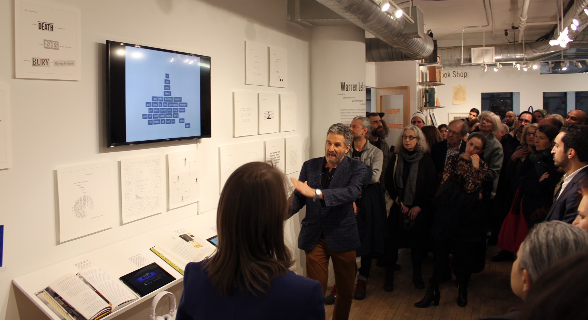 Lehrer gives a tour of his exhibition to a packed gallery
