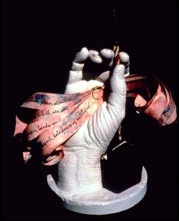 plaster hand holds strips of red paper with handwriting