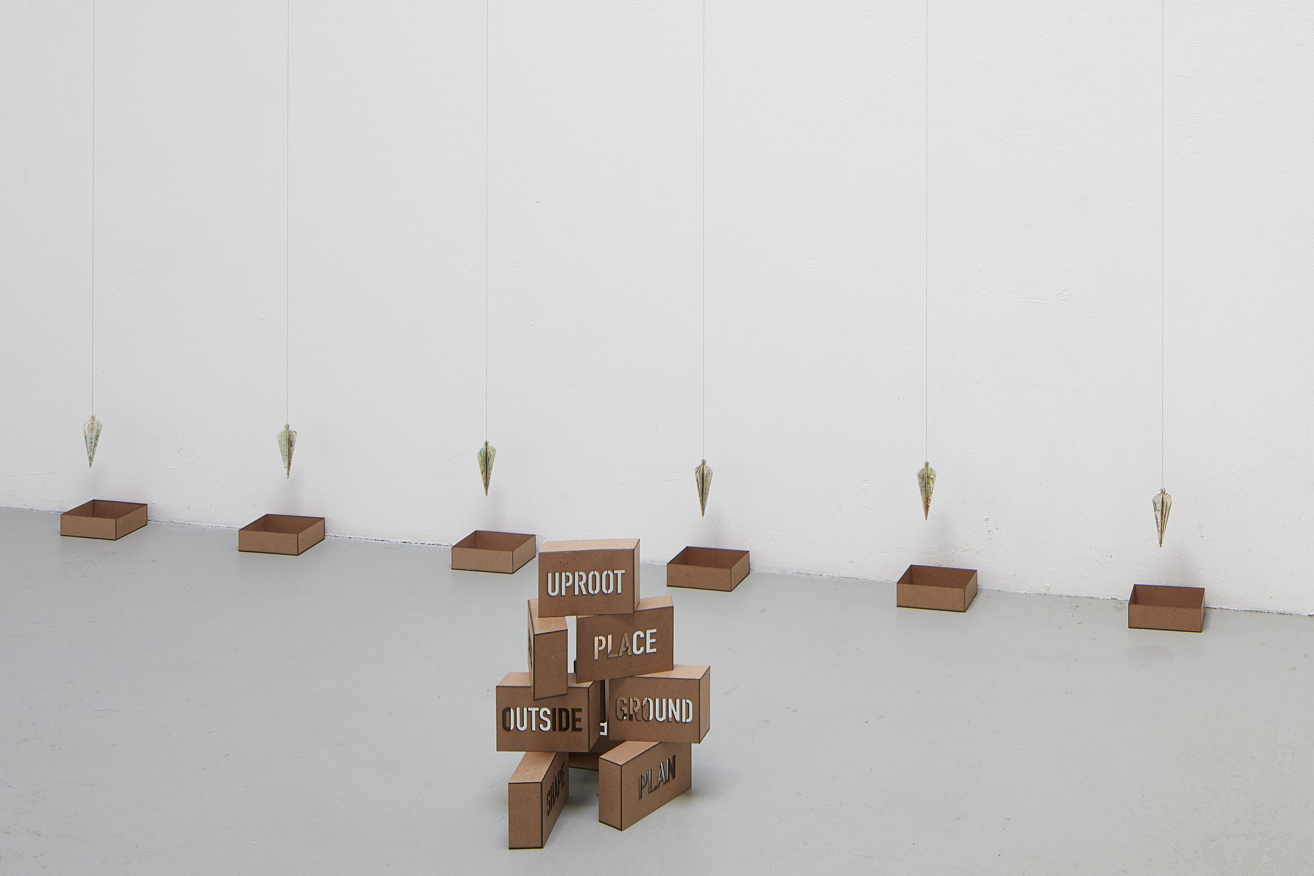 Installation of artwork that resembles a stavk of bricks and hanging plumb lines