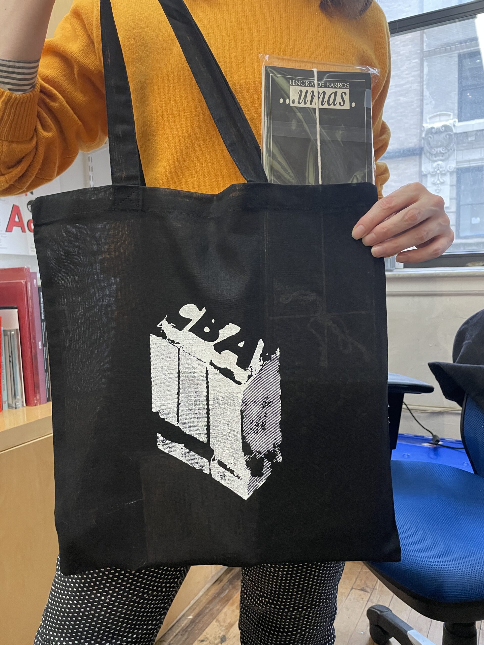 black tote bag with white print of lead type spelling "CBA"