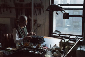A photo of artist, Amina Ahmed in her studio, carefully touching a stack of books