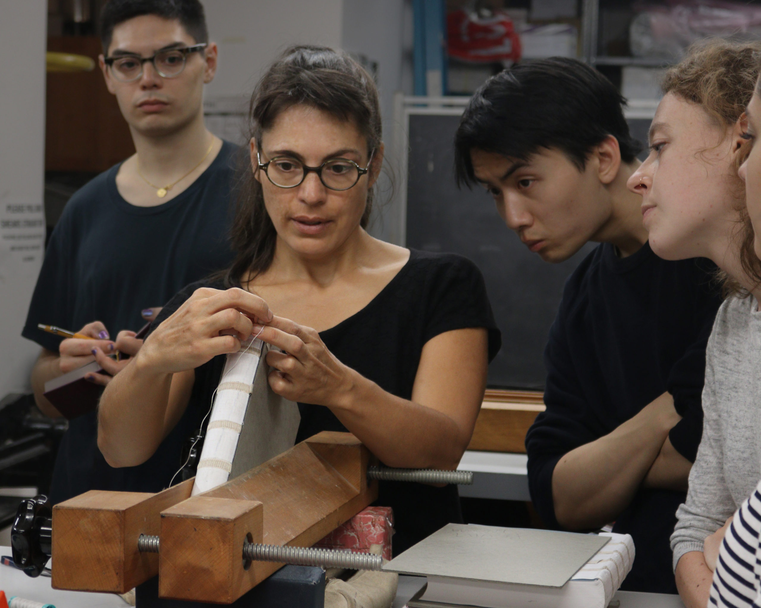 Celine Lombardi demonstrates how to sew headbands to a group of students