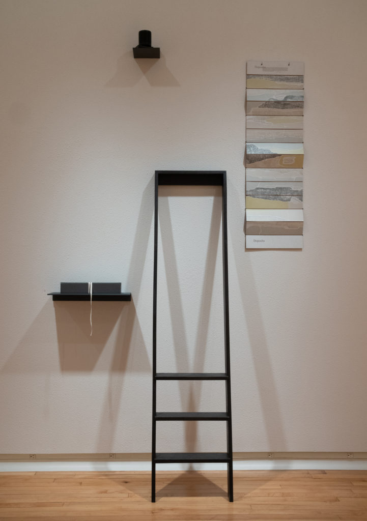 ladder leans against the wall with accordion artist's book hanging beside it