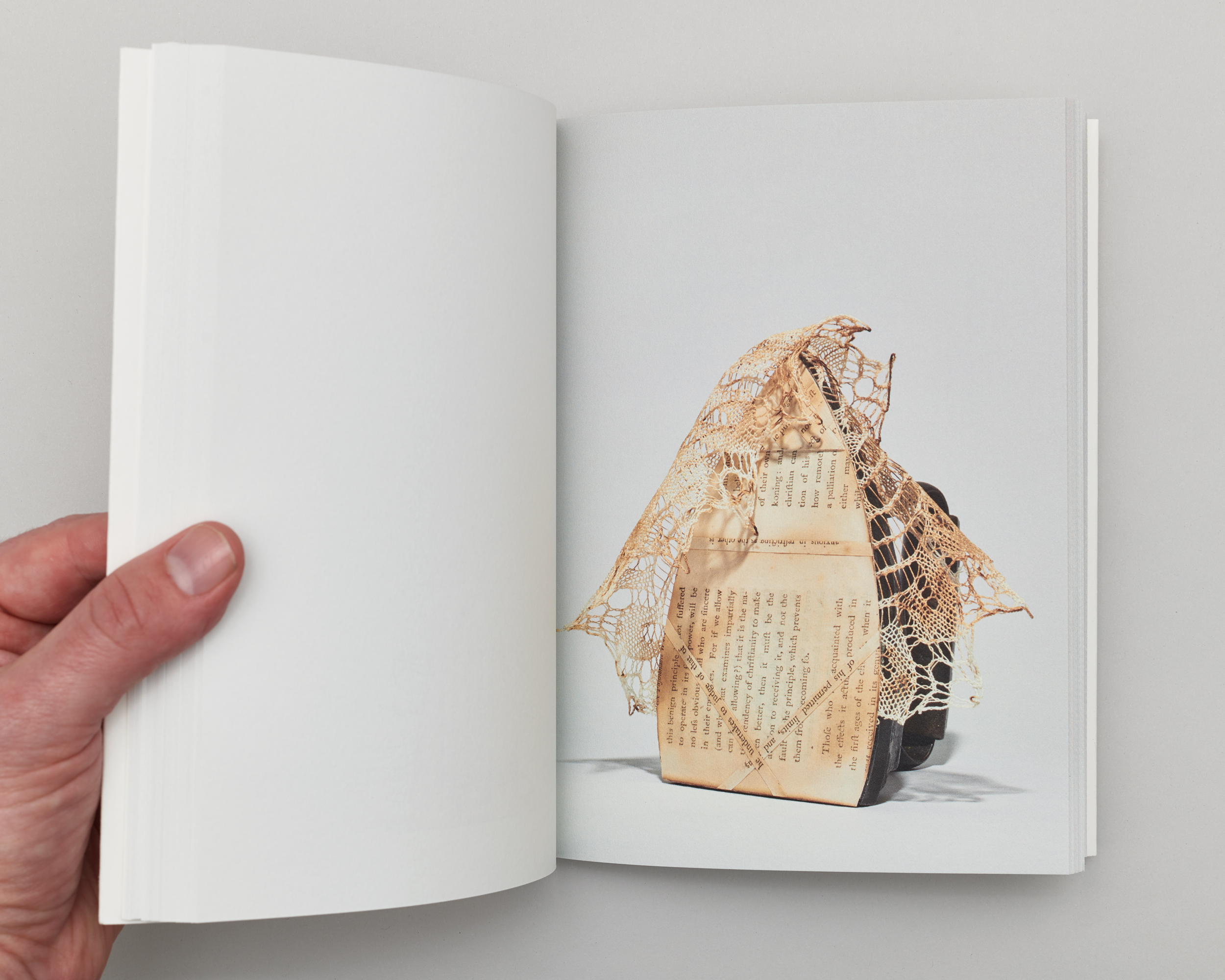 Open book with a photograph of an iron on the right page. The iron's base is covered with book pages and wrapped in lace.