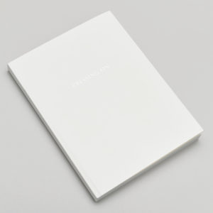 Closed white book on a light grey surface