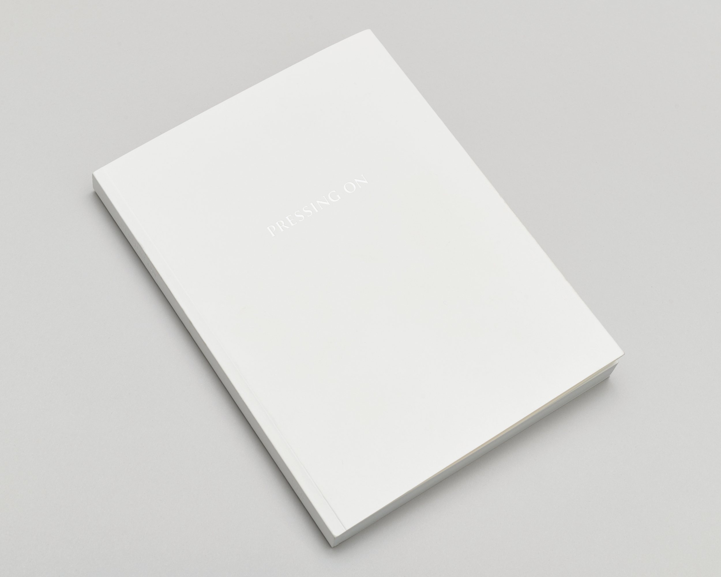 Closed white book on a light grey surface