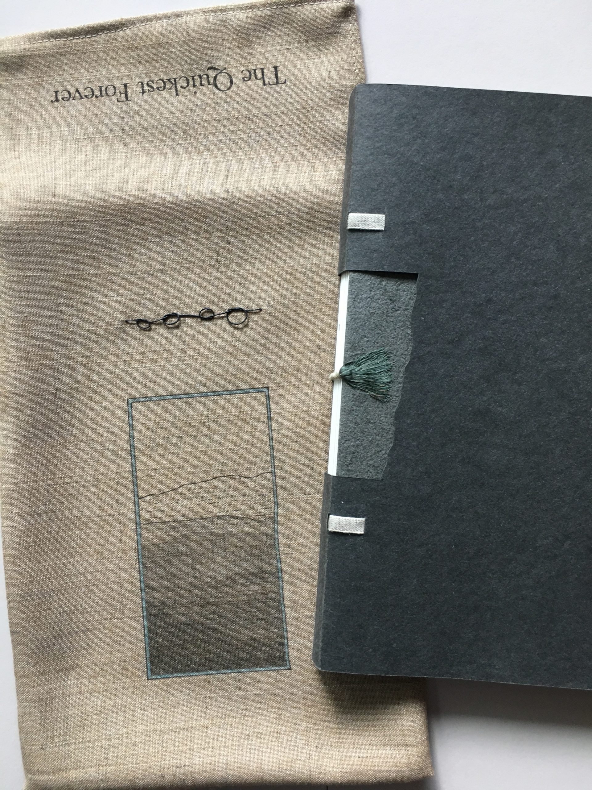 closed gray artist's book sitting on top of a linen pouch