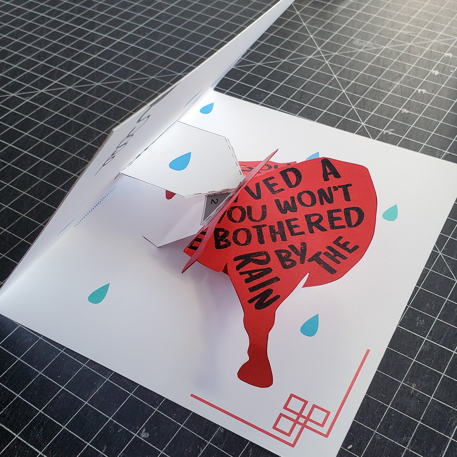 A year of the Ox pop-up card is halfway closed. There is half of a red Ox with words written within the border.
