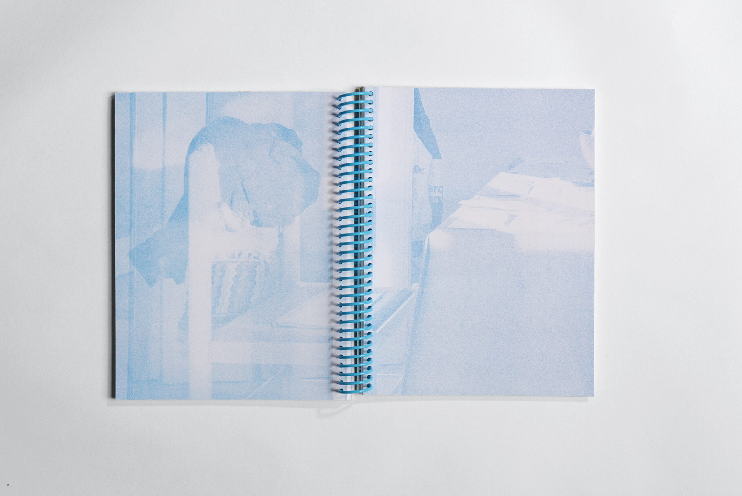 Risograph printed exhibition catalog with light blue image on white paper, bound with a blue spiral coil.