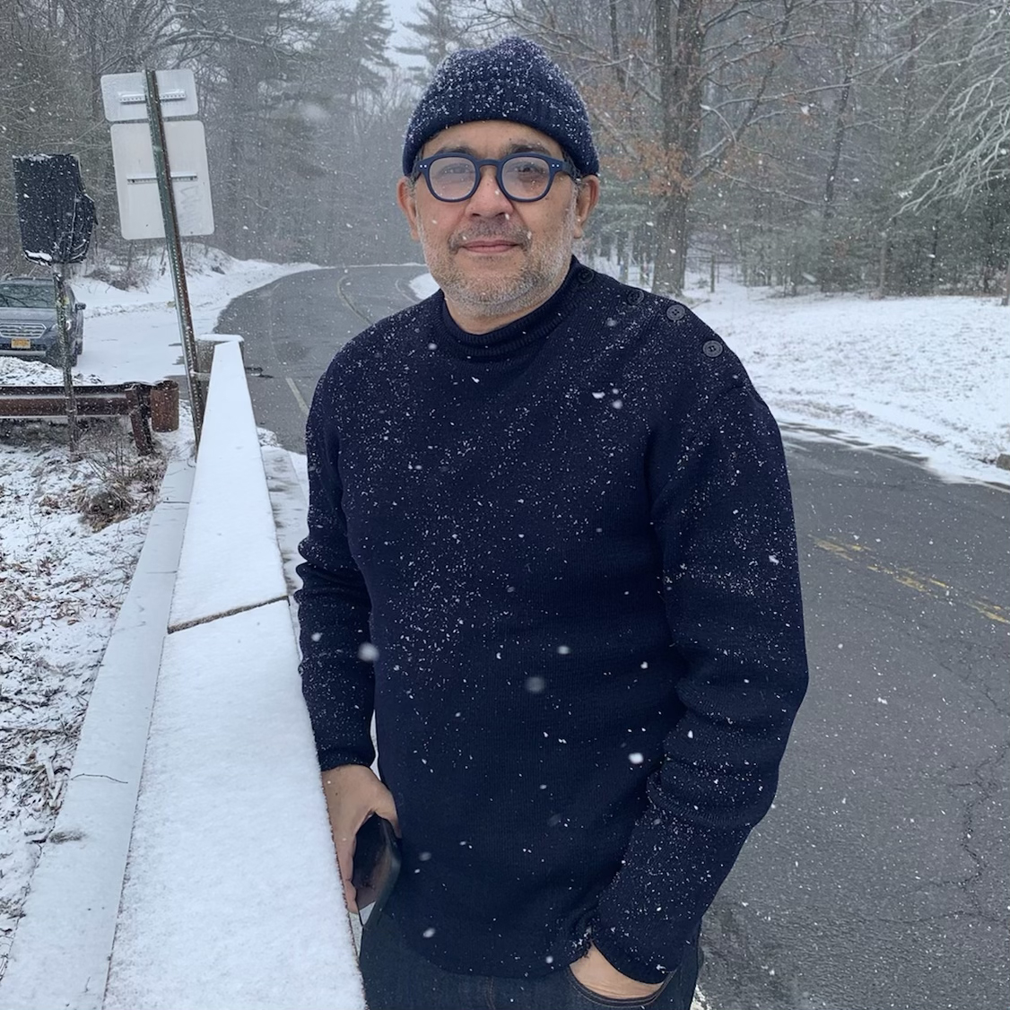 man wearing all navy blue in the snow with glasses