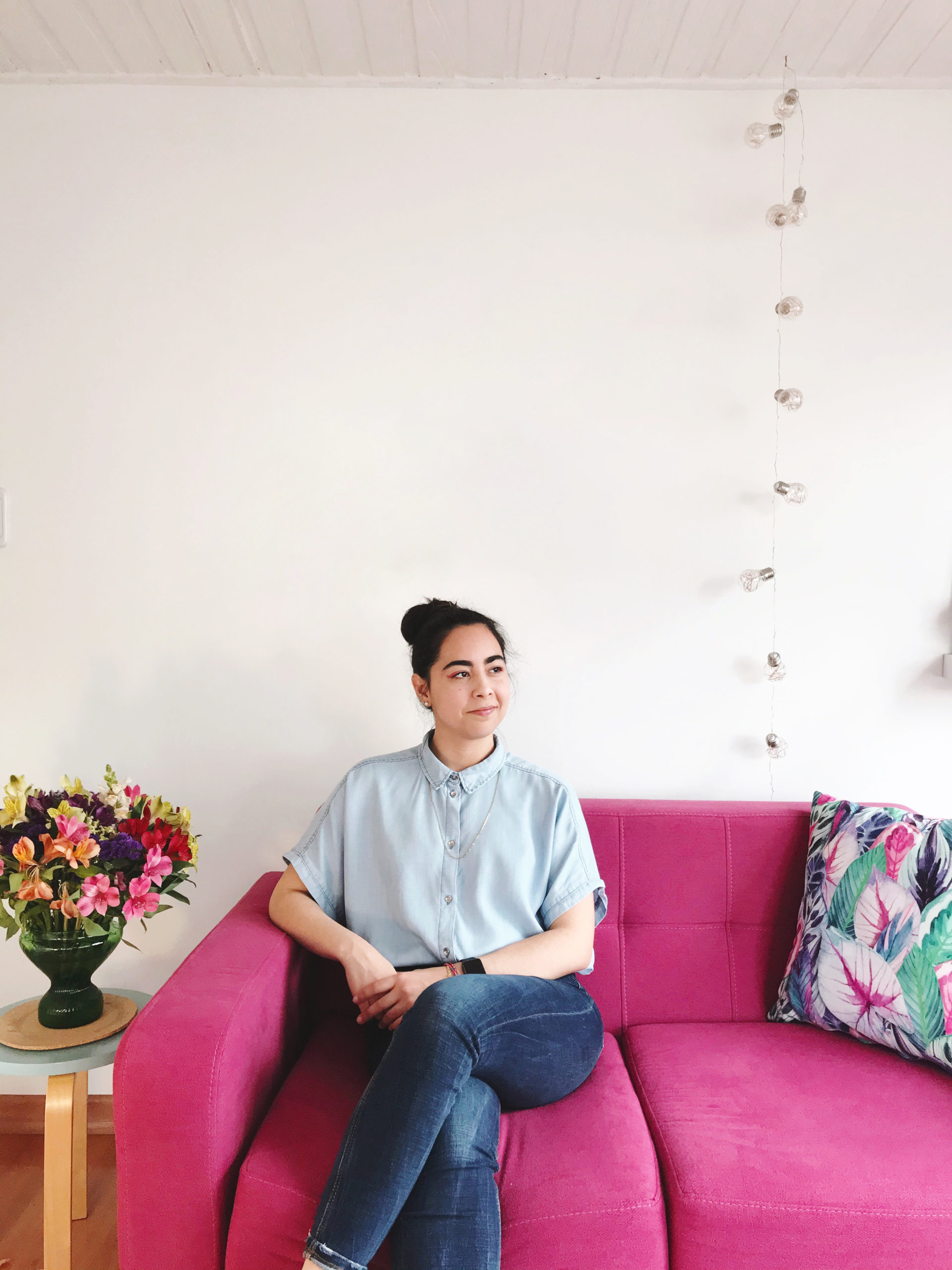 Nubia Navarro sitting on a pink couch against a mostly blank white wall.