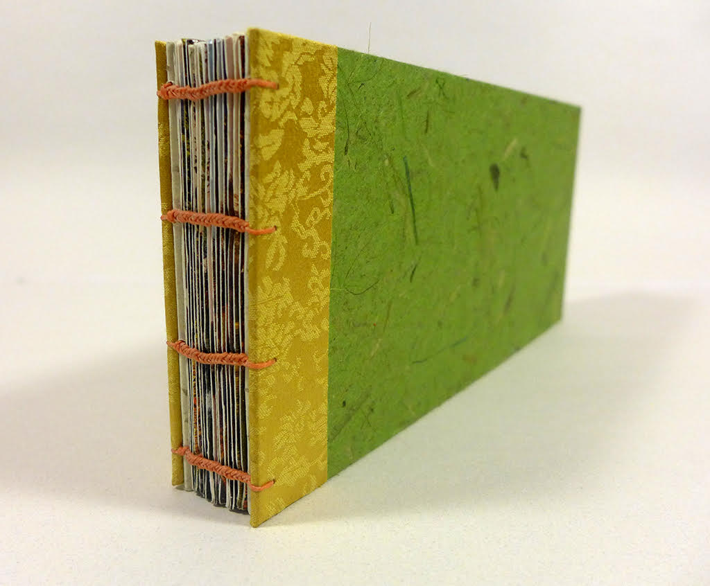 An image of a book with a green cover, yellow detail near the spine, and an open spine stitched with orange thread.