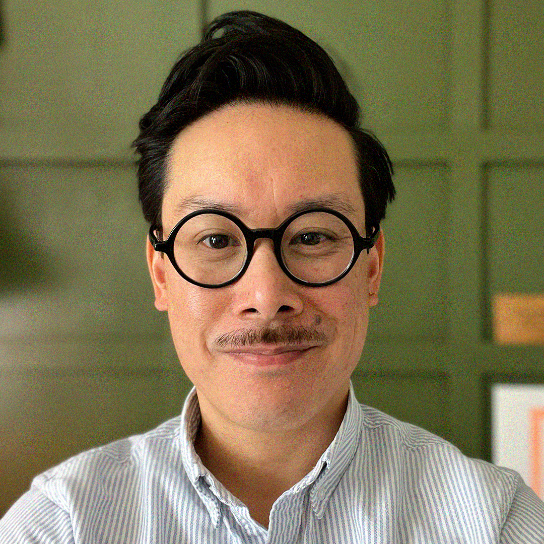 man with dar hair, round glasses and a short mustache