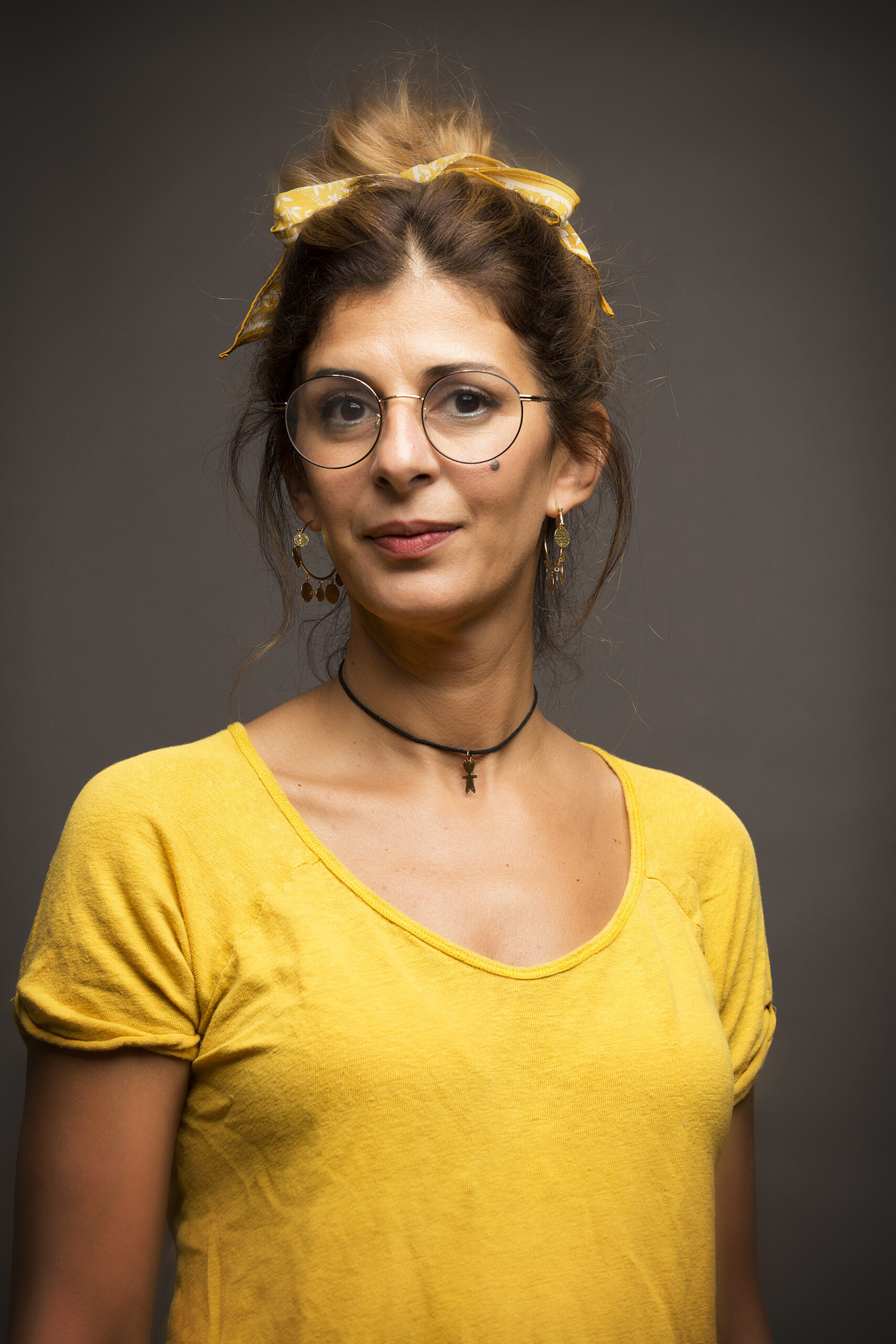 woman with hair loosly tied up wearing glasses
