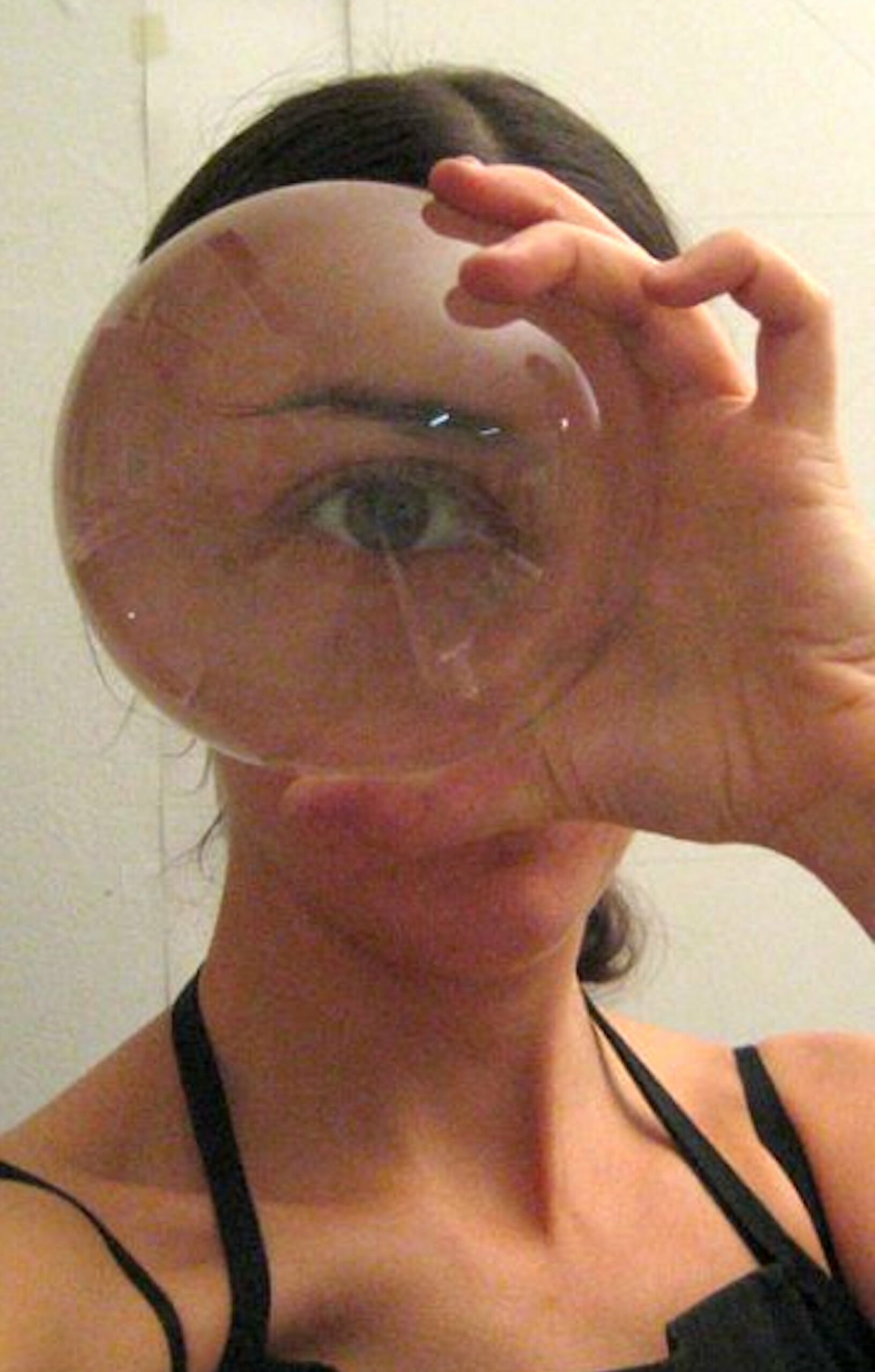 Alta hold a glass sphere in front of their eye, magnifying their eye so it takes up their whole face.