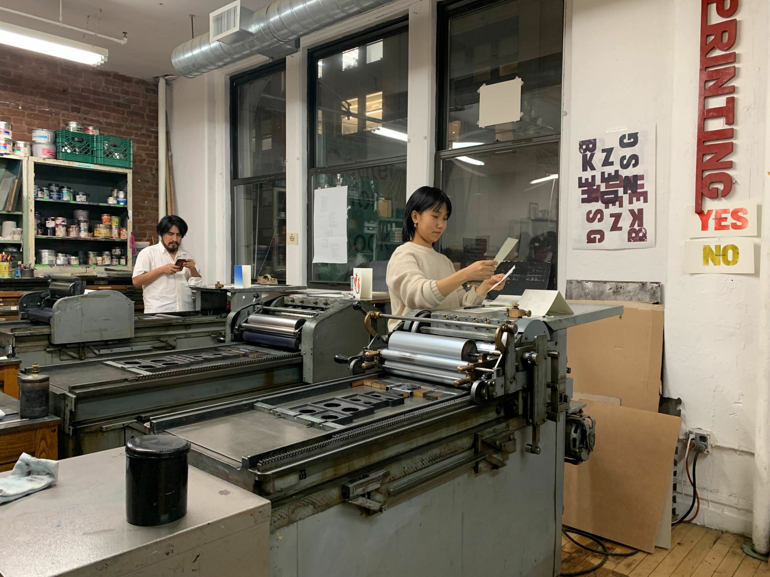 A view of the CBA printshop with Caslon working on the Number 4 in the foreground and Oswaldo working on the Uni 1 in the background.